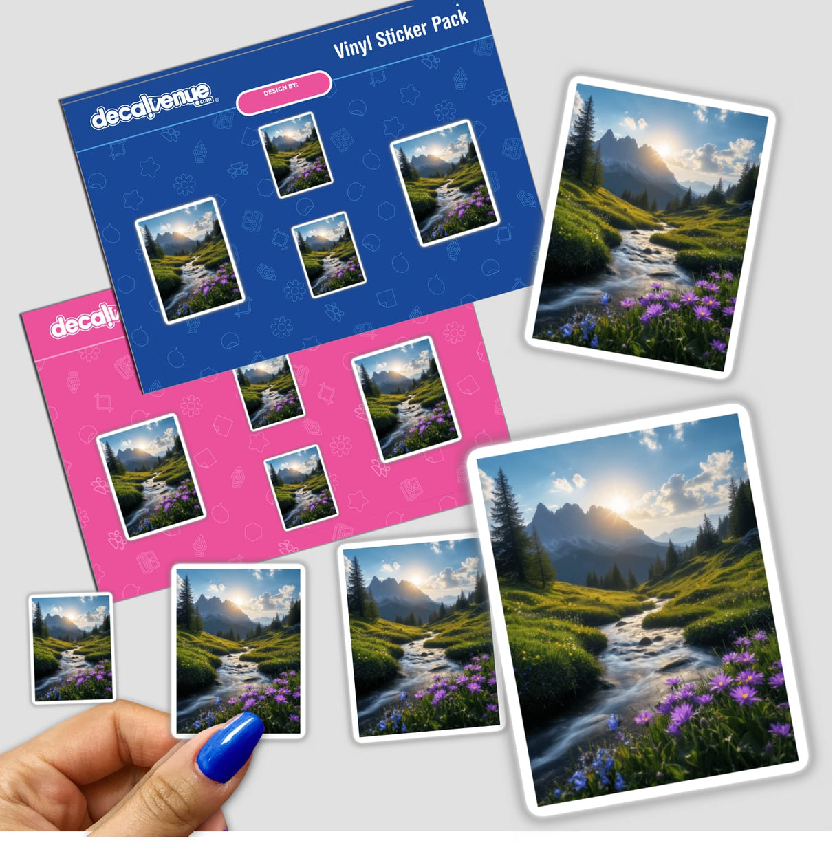 A hand holds a sticker pack titled Mountain Stream at Sunrise featuring a river, mountains, and wildflowers, epitomizing Decal Venue's unique vinyl sticker and digital art offerings.