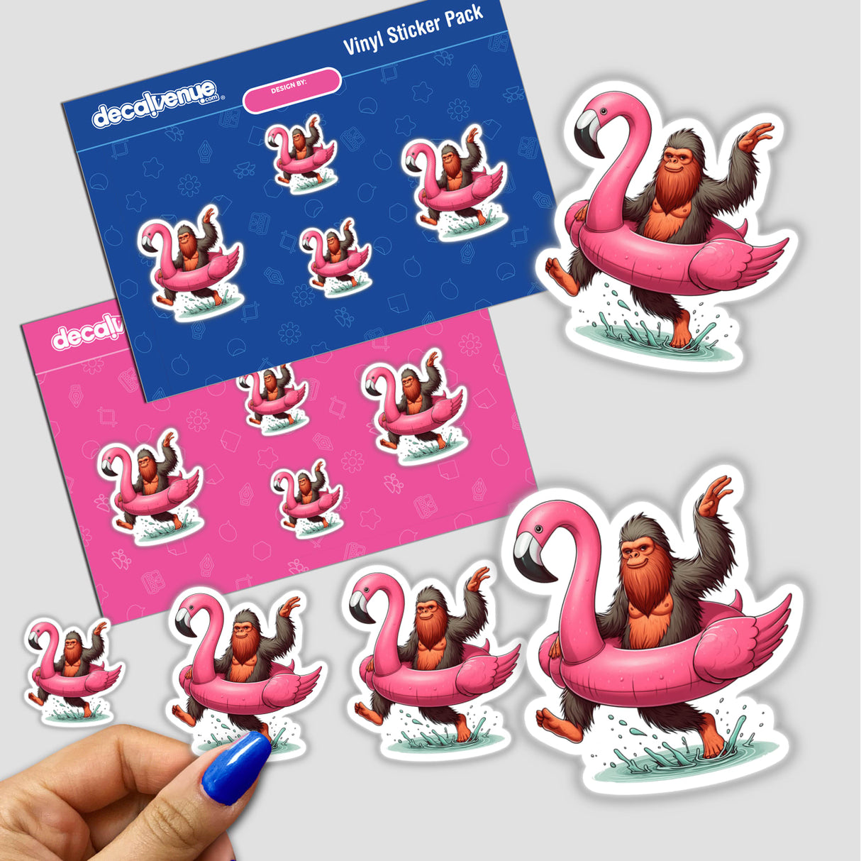 Sticker featuring Sasquatch Splashing in Flamingo Float, held by a hand with blue nail polish. Part of Decal Venue's unique vinyl stickers and digital art collection.