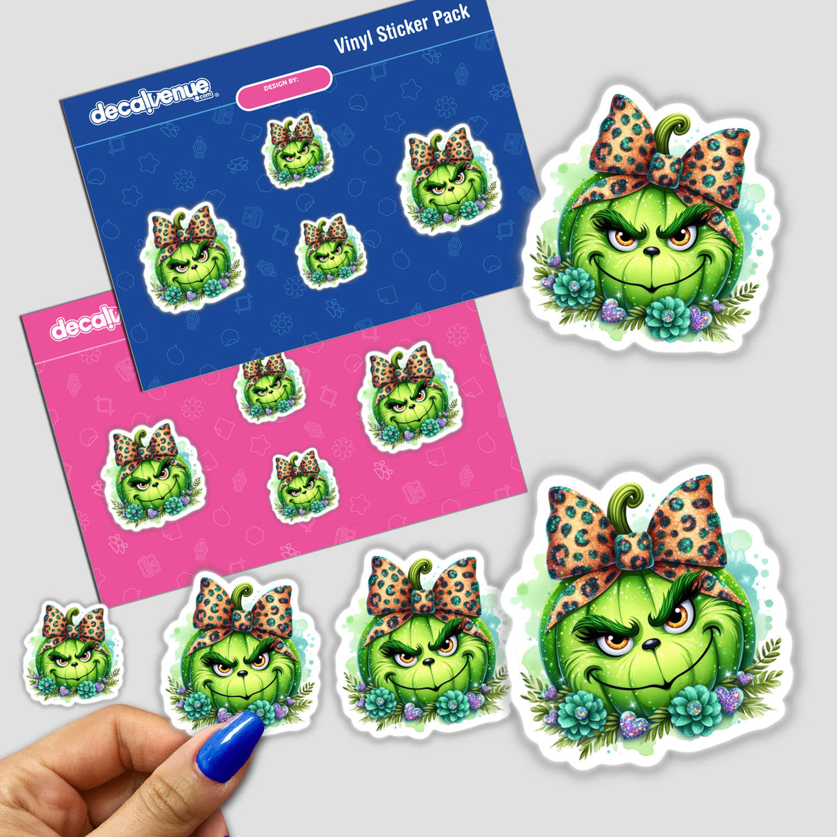 A hand holding a Glitter Leopard Bow Green Grouch Pumpkin Face sticker from a pack of cartoon character stickers.