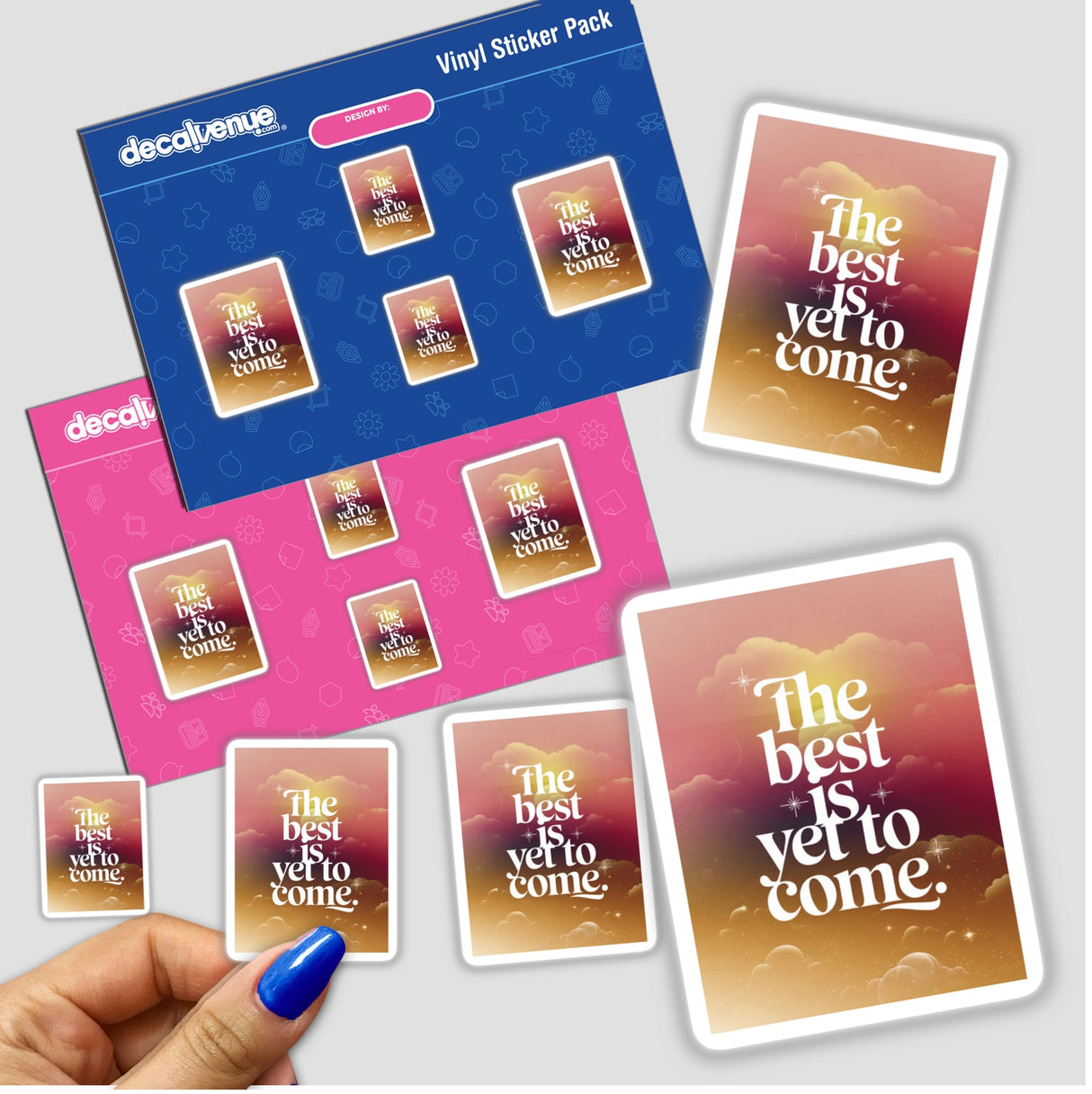 Hand with blue nail polish holding 'The best is yet to come' sticker pack from Decal Venue, showcasing unique vinyl stickers available as both physical decals and digital artwork.