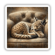 Lynx Cub Curled Up on Cushioned Chair, depicted in a painting available as stickers or digital artwork from Decal Venue.