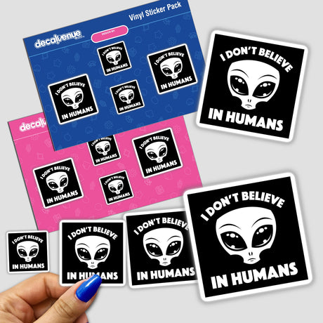 Hand holding I Don’t Believe In Humans Cartoon Alien In White stickers featuring alien faces and text, showcasing unique vinyl art from Decal Venue.