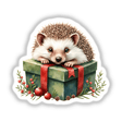 Hedgehog perched on a Christmas present box, available as a sticker or digital artwork from Decal Venue. The image captures the hedgehog's charming presence atop the festive package.