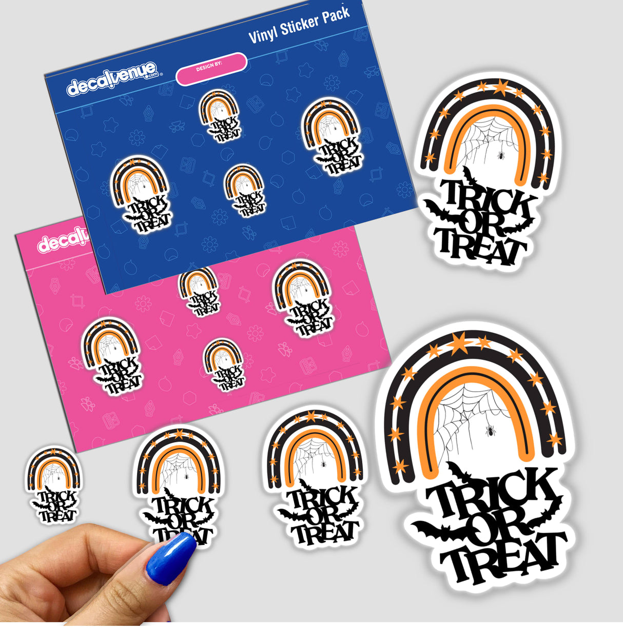 Hand holding a sticker pack featuring the Trick or Treat black and orange rainbow with bats and a spider web, from Decal Venue's unique stickers collection.