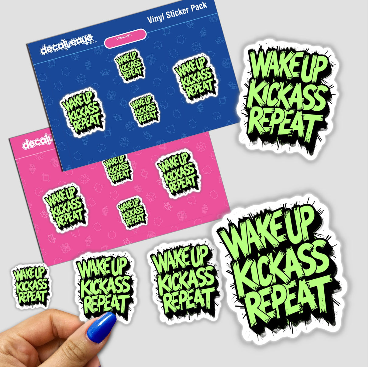 Hand holding Wake Up Kick Ass Repeat stickers, available as vinyl stickers or digital artwork from Decal Venue, showcasing a motivational quote in a bold design.