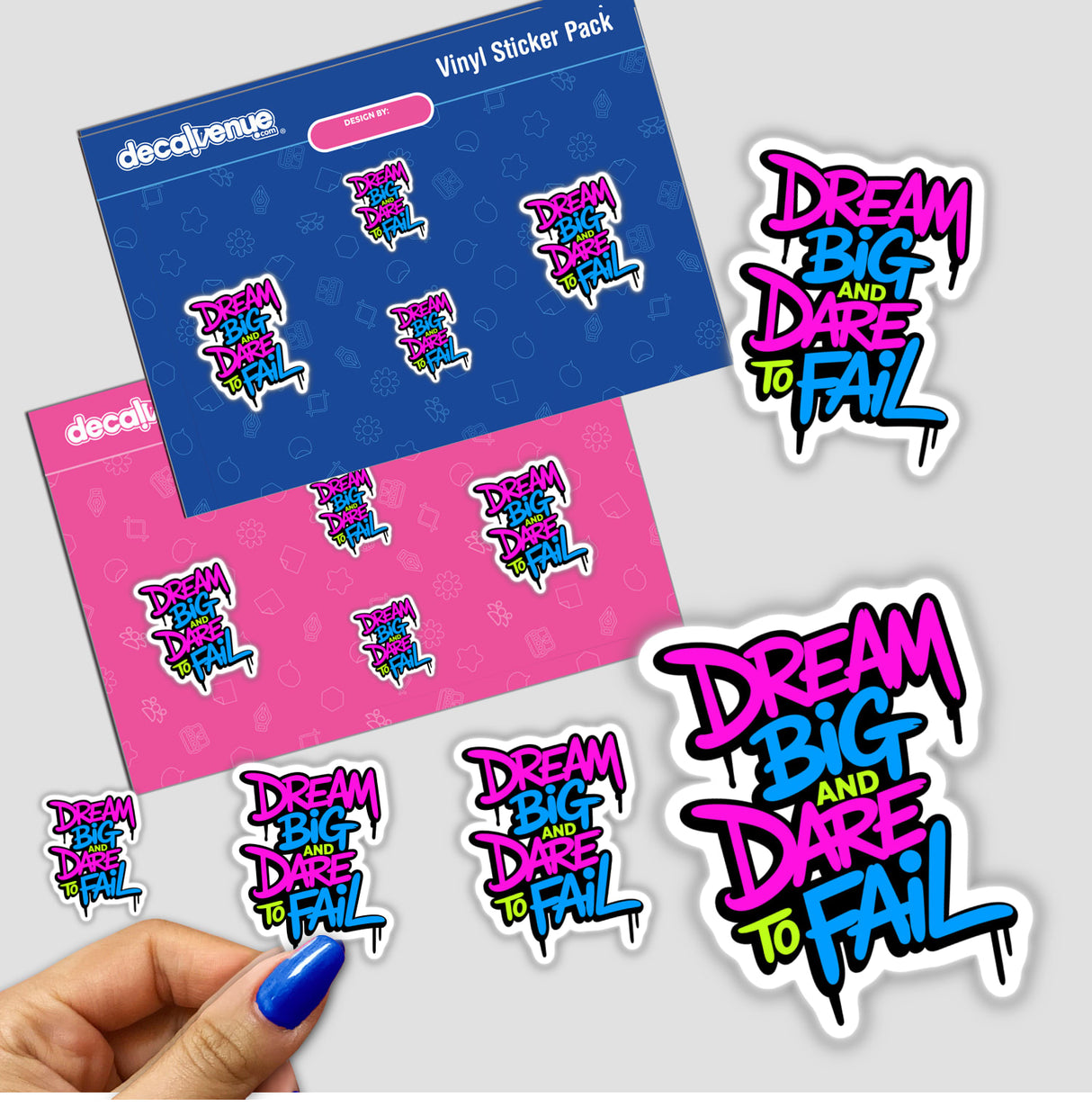 Hand holding a Dream Big And Dare To Fail motivational sticker, showcasing colorful text design, part of Decal Venue's unique vinyl sticker and digital art collection.
