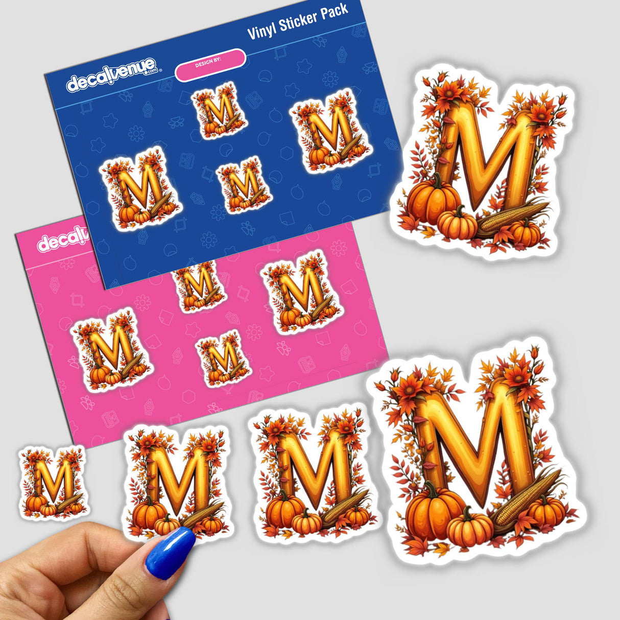 Hand holding Fall Aesthetic Letter M Clipart sticker featuring pumpkins and leaves, available as stickers or digital artwork with commercial rights.