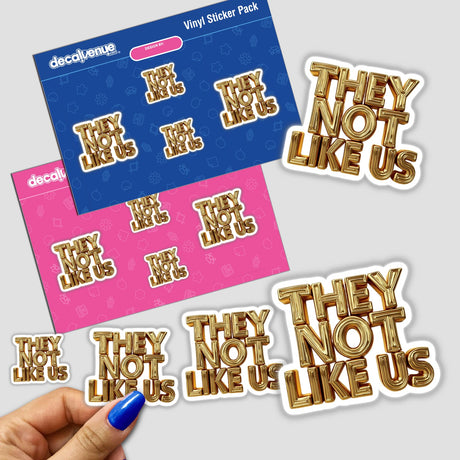 Hand holding a Gold They Not Like Us sticker, featuring elegant gold text on a white background, part of Decal Venue's unique sticker collection.