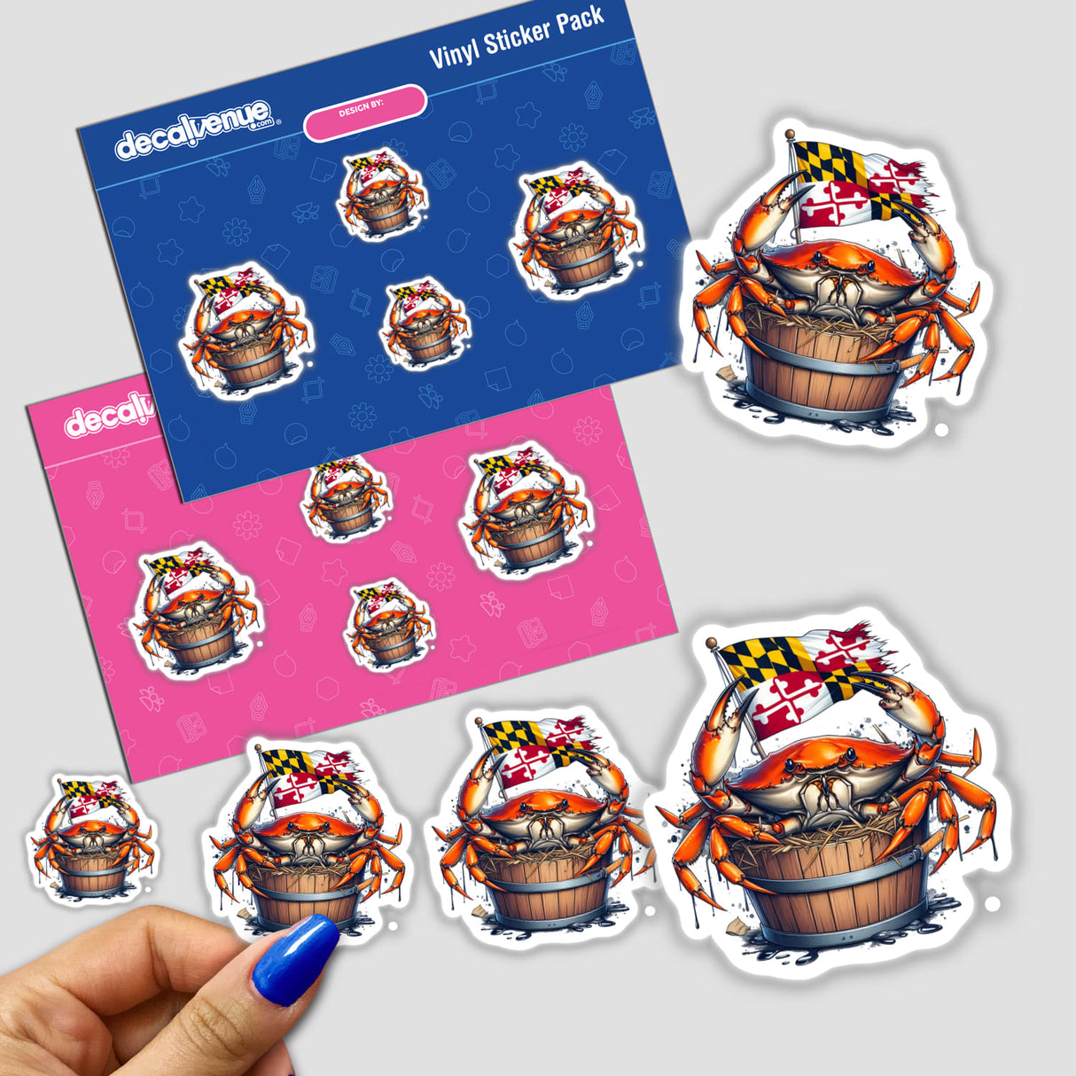 Maryland Crab in a Bushel Bucket vinyl-sticker pack from Decal Venue, featuring a crab clutching a Maryland flag. Includes blue and pink backing sheets with four die-cut stickers, one held by a hand.