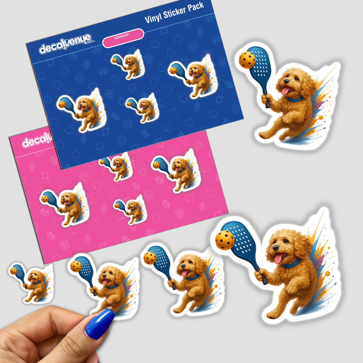 Vinyl sticker pack titled Cockapoo Dog Playing Pickleball featuring cute poodle-type puppies mid-swing with paddles and balls. A hand peels a small sticker from backing sheets, showcasing playful designs.