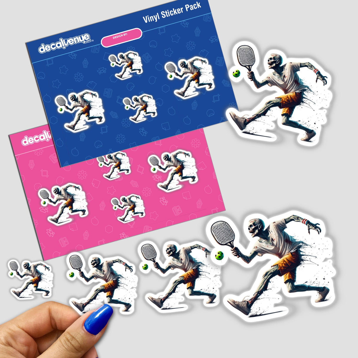 Person holding a sticker titled Zombie Playing Pickleball featuring a cartoon skeleton with a tennis racket.