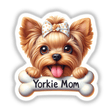 Adorable Yorkshire Terrier puppy with a polka dot bow, holding a "Yorkie Mom" bone-shaped sign in front of a white background. The cute, fluffy dog has a happy, playful expression with its tongue sticking out, showcasing its endearing personality.