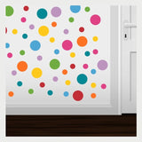 Vibrant polka dot wall decals in various sizes and colors surrounding a white door, creating a playful and decorative wall design.